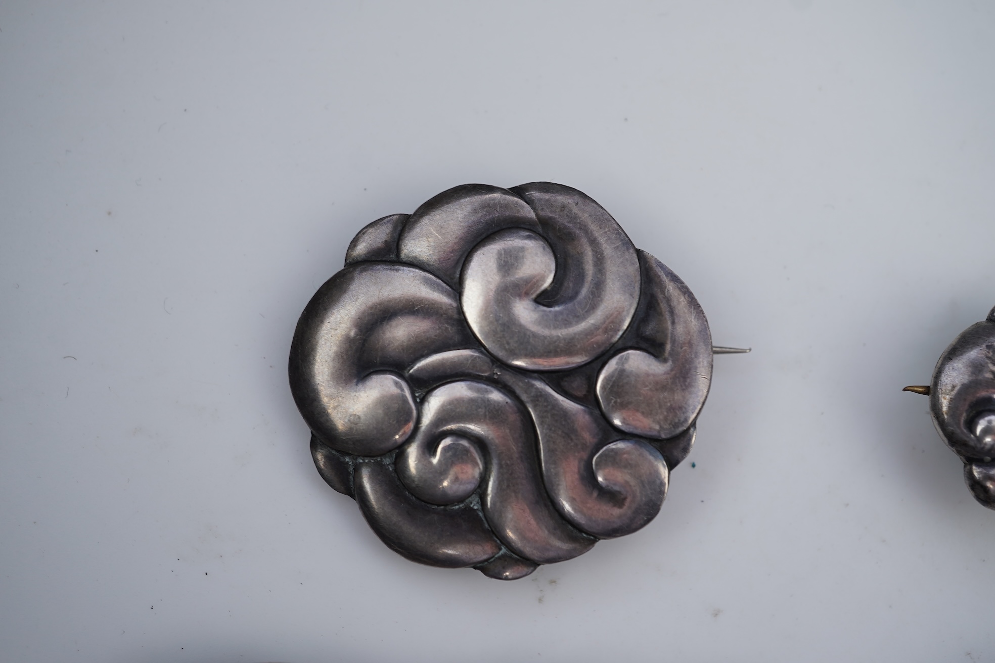 An Arts & Crafts silver slide and three silver brooches, probably Denmark, first half 20th century
